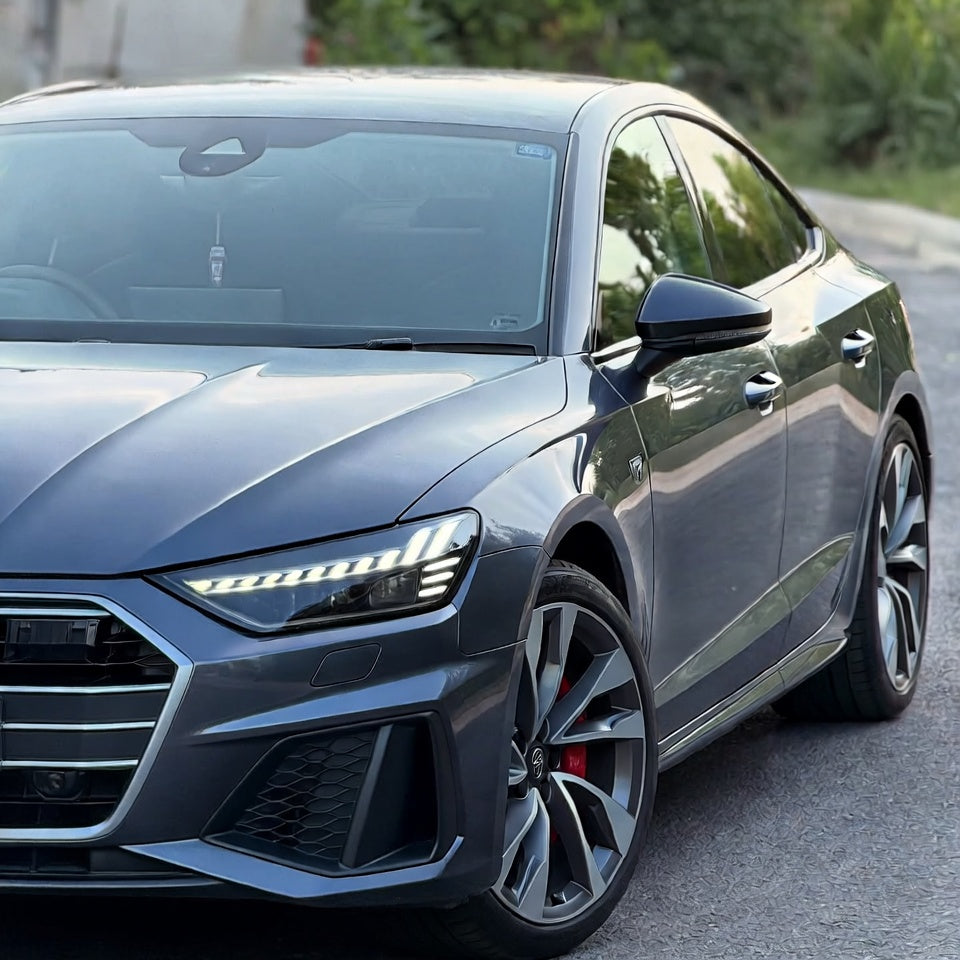 Gray Audi car parked on a road with greenery in the background